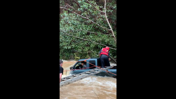 First responders in Tennessee work to rescue woman and child from a swollen creek. - Sputnik International