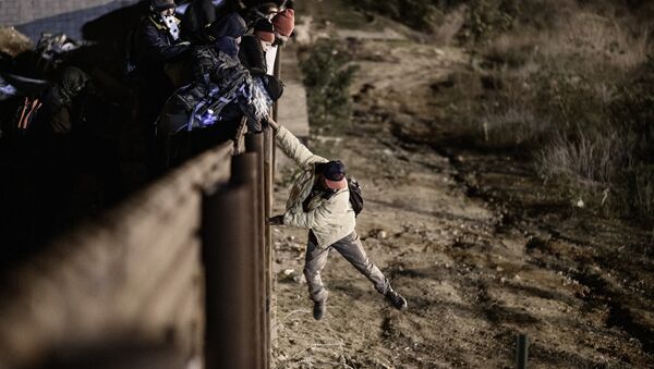A migrant jumps the border fence to get into the U.S. side to San Diego, Calif., from Tijuana, Mexico, Tuesday, Jan. 1, 2019 - Sputnik International