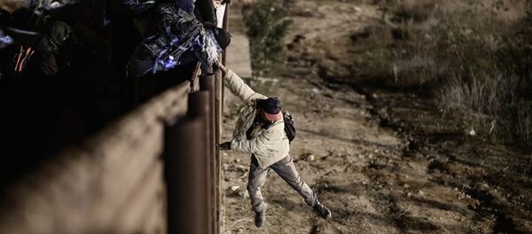 A migrant jumps the border fence to get into the U.S. side to San Diego, Calif., from Tijuana, Mexico, Tuesday, Jan. 1, 2019 - Sputnik International