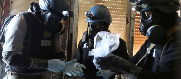 A U.N. chemical weapons expert, wearing a gas mask, holds a plastic bag containing samples from one of the sites of an alleged chemical weapons attack in the Ain Tarma neighbourhood of Damascus, Syria. (File) - Sputnik International