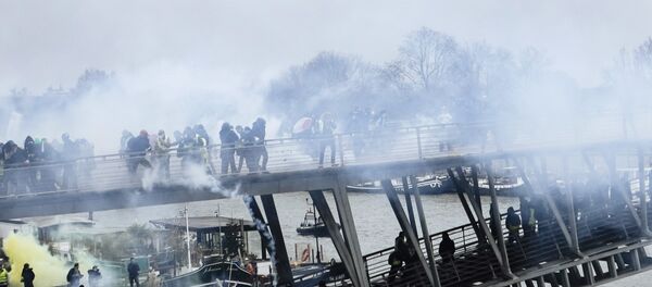 Tear gas is thrown by riot police as demonstrators wearing yellow vests try to cross a pedestrian bridge during march in Paris, Saturday, Jan. 5, 2019. Tear gas is thrown by riot police as demonstrators wearing yellow vests try to cross a pedestrian bridge during march in Paris, Saturday, Jan. 5, 2019. - Sputnik International