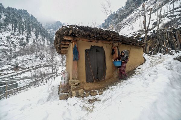 An Indian Kashmiri woman walks with firewood next to a rural home on the outskirts of Srinagar on January 9, 2019. - Sputnik International