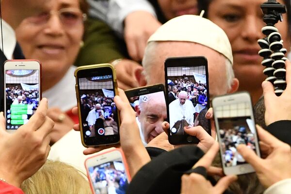 The faithful greet Pope Francis (Rear) and take photos of him with their mobile phone upon his arrival for the weekly general audience on January 9, 2019 at Paul-VI hall in the Vatican. - Sputnik International