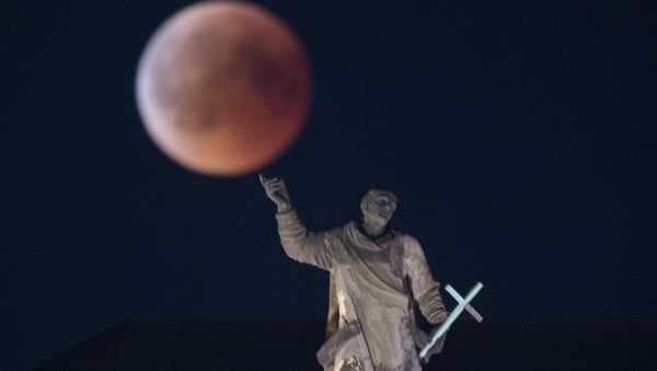 The full moon appears behind the Mattielli-statue on the Hofkirche church during a blood moon eclipse over Dresden, eastern Germany, on July 27, 2018 - Sputnik International