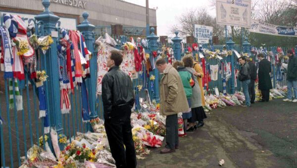People looking at the hundreds of scarves and flowers which were left in tribute at Hillsborough in the aftermath of the disaster - Sputnik International