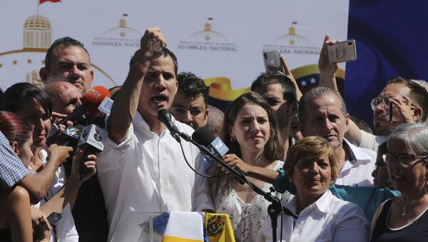 Juan Guaido, president of National Assembly, shows marks on his wrists, which he says are from handcuffs, to supporters at a rally in Caraballeda, Venezuela, Sunday, Jan. 13, 2019. The new head of Venezuela's increasingly defiant congress was pulled from his vehicle and briefly detained by police Sunday, a day after the U.S. backed him assuming the presidency as a way out of the country's deepening crisis. Guaido's wife Fabiana Rosales stands next to him, right. (AP Photo/Fernando Llano) - Sputnik International