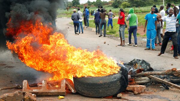 Protesters stand behind a burning barricade during protests on a road leading to Harare, Zimbabwe, January 15, 2019 - Sputnik International