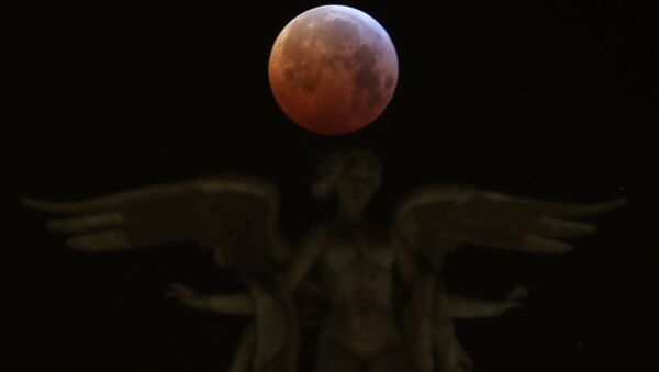 The moon is seen over Victoria Alada statue on the top of Metropoli building during a total lunar eclipse, known as the Super Blood Wolf Moon in Madrid, Spain, January 21, 2019 - Sputnik International