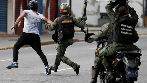 Security forces run after a demonstrator during a protest of opposition supporters against Venezuelan President Nicolas Maduro's government in Caracas, Venezuela - Sputnik International