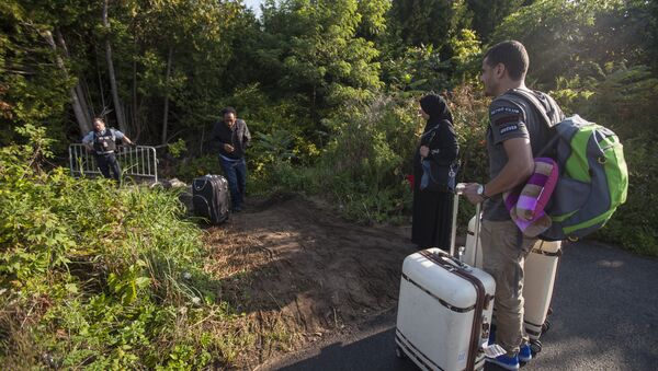 RCMP officers speaks with migrants as they prepare to cross the US/Canada border illegally near Hemmingford, Quebec, August 20, 2017 - Sputnik International