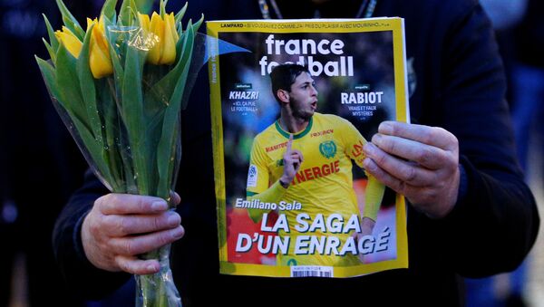 A man holds a sports magazine and yellow tulips as fans gather in Nantes' city center after news that newly-signed Cardiff City soccer player Emiliano Sala was missing after the light aircraft he was travelling in disappeared between France and England the previous evening, according to France's civil aviation authority, France, January 22, 2019. - Sputnik International