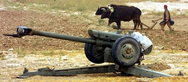 An Afghan peasant ploughs near Soviet-made D-30 howitzers just outside the village of Ai-Khanum, Northern Afghanistan, Friday Nov. 9, 2001. - Sputnik International