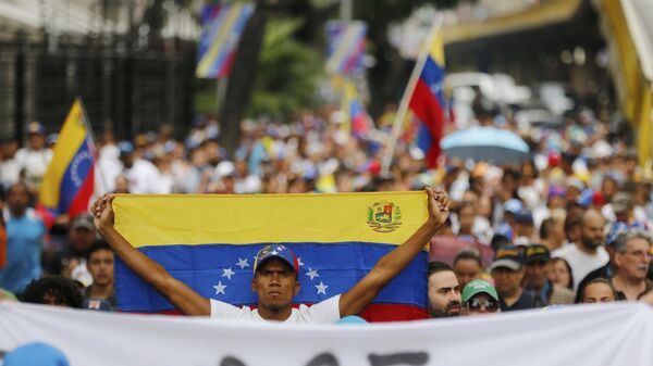 An opposition member holds a Venezuelan national flag during a protest march against President Nicolas Maduro in Caracas, Venezuela, Wednesday, Jan. 23, 2019. - Sputnik International