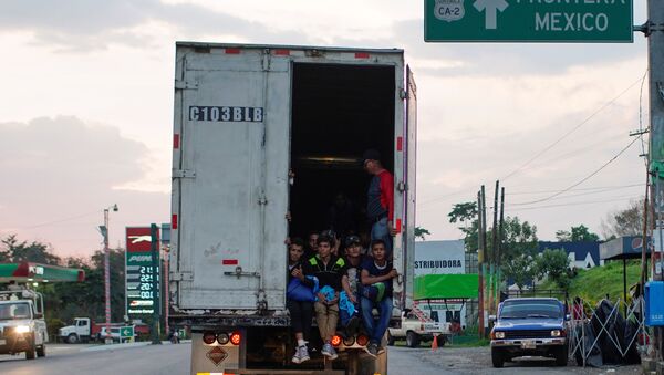 Immigrants pass by a highway sign that reads in Spanish: Mexico Border, as they take a lift in the back of a truck during their journey towards the United States, in Pajapita, Guatemala, January 17, 2019 - Sputnik International