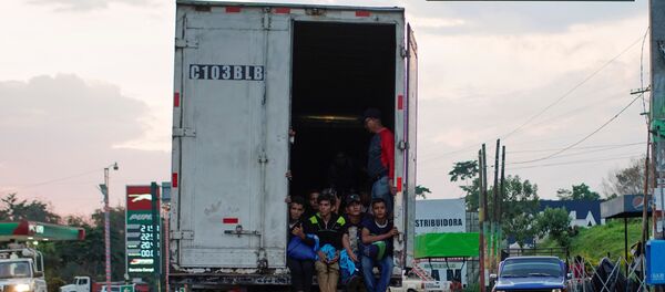 Immigrants pass by a highway sign that reads in Spanish: Mexico Border, as they take a lift in the back of a truck during their journey towards the United States, in Pajapita, Guatemala, January 17, 2019 Immigrants pass by a highway sign that reads in Spanish: Mexico Border, as they take a lift in the back of a truck during their journey towards the United States, in Pajapita, Guatemala, January 17, 2019 - Sputnik International