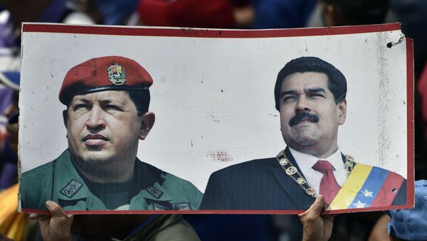 A supporter of President Nicolas Maduro's government holds a banner with the portraits of late Venezuelan president Hugo Chavez (L) and President Nicolas Maduro, while taking part in a march, on the anniversary of 1958 uprising that overthrew military dictatorship in Caracas on January 23, 2019. - Sputnik International