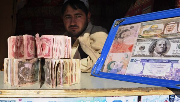A Pakistani man holds banknotes as he waits for the customers at his currency exchange shop in Quetta on November 22, 2010 - Sputnik International