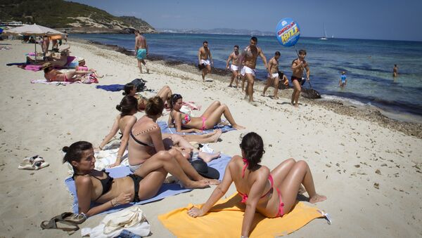 Girls sunbathing watch boys promoting a discotheque at Playa des Cavallet beach in Sant Josep de sa Talaia, on Ibiza Island on July 10, 2015. - Sputnik International