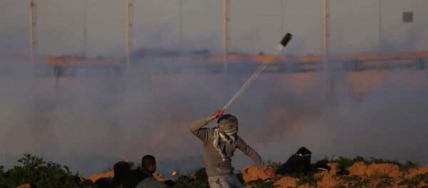 A Palestinian demonstrator hurls stones at Israeli troops during a protest at the Israel-Gaza border fence, in the southern Gaza Strip January 18, 2019 - Sputnik International