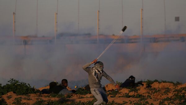 A Palestinian demonstrator hurls stones at Israeli troops during a protest at the Israel-Gaza border fence, in the southern Gaza Strip January 18, 2019 - Sputnik International