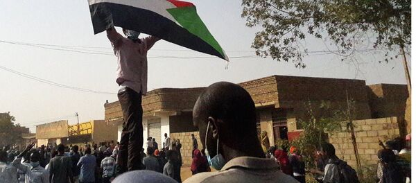 Demonstrators against President al-Bashir hold up a Sudanese flag during protests in Omdurman in January 2019 Demonstrators against President al-Bashir hold up a Sudanese flag during protests in Omdurman in January 2019 - Sputnik International