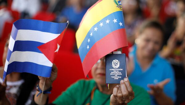 A supporter of Venezuela's President Nicolas Maduro holding a copy of the Venezuelan constitution and flags of Venezuela and Cuba, takes part in a gathering in support of his government outside the Miraflores Palace in Caracas, Venezuela January 26, 2019 - Sputnik International