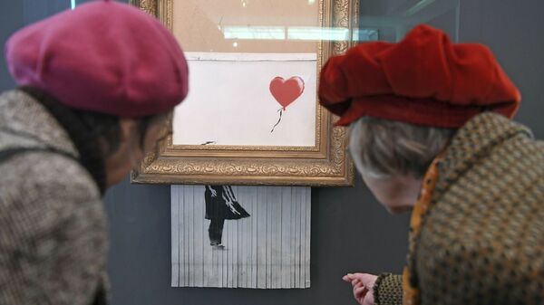 Посетители смотрят на самоуничтожившуюся после продажи на аукционе картину художника Бэнкси Девочка с воздушным шаром, которая теперь называется Любовь в мусорном баке, в Музее современного искусства в Баден-Бадене, Германия - Sputnik International