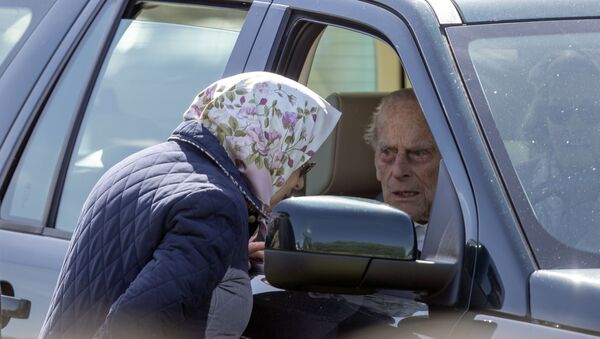 Britain's Prince Philip sits in the driving seat of a car, talking to his wife, Queen Elizabeth II - Sputnik International