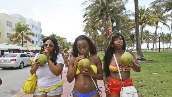 Tai Derrow, left, of Houston, Texas, Shaena Wilson, center, of Orlando, Fla., and Sprano Samuels, of Houston, Texas., drink coconut water as they walk down Ocean Drive while they enjoy their Memorial Day weekend in the South Beach section of Miami, Beach, Fla., Friday, May 28, 2010. - Sputnik International