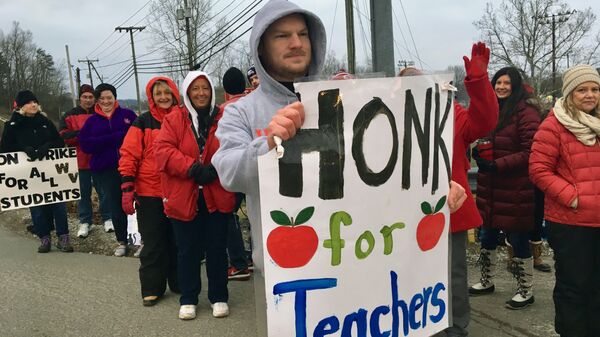 Striking teachers wave at passing cars outside Poca High School Tuesday, Feb. 19, 2019, in Poca, W.Va. Poca is in Putnam County, the only county in the state where public schools were held on the first day of the strike - Sputnik International