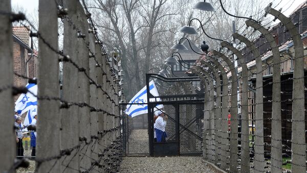 Participants with Israeli flags pass a barbed wire fence at the former Nazi German Auschwitz-Birkenau death camp during the 'March of the Living' at in Oswiecim, Poland on April 16, 2015 - Sputnik International