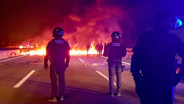 Police officers stand next to burning barricades settled to block the AP7 highway during a regional strike near Girona, Spain, February 21, 2019 - Sputnik International