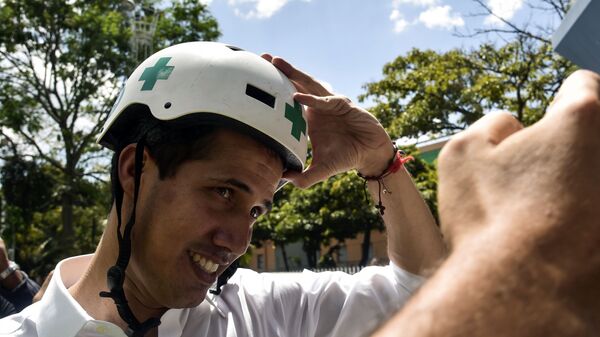 Venezuelan opposition leader and self declared acting president Juan Guaido wears a Green Cross helmet as he posses for a picture with volunteers of the movement Aid and Freedom Venezuela Coalition after delivering a speech in Caracas, on February 16, 2019 - Sputnik International