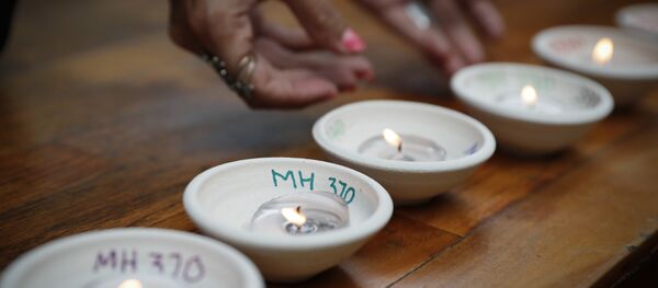 Relative of passengers on board the missing Malaysia Airlines Flight MH370 light up candle during the Day of Remembrance for MH370 event - Sputnik International
