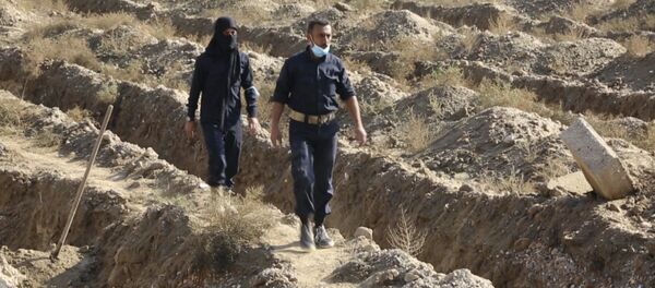 This frame grab from a video provided on Thursday, Nov. 22, 2018, shows Syrian workers of a Raqqa group walk at the site of a mass grave believed to contain the bodies of civilians and Islamic State militants, in Raqqa. A local official in the city of Raqqa says more than 500 bodies have so far been exhumed from one of the largest mass graves discovered in the city. The northern Syrian city was once the de facto capital of the Islamic State group and was liberated in a campaign that ended more than a year ago, but rescuers and early recovery teams continue to locate mass graves scattered around the city. - Sputnik International
