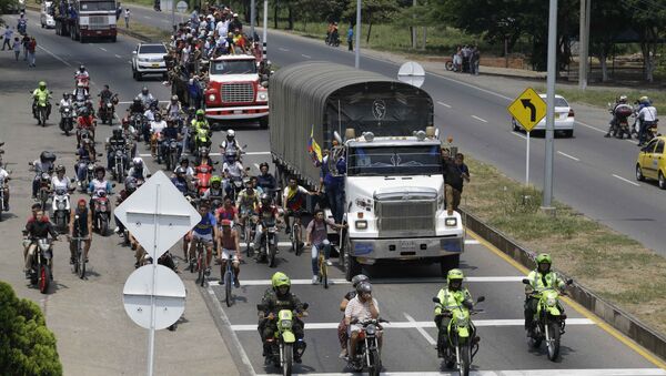 People ride atop and alongside semi-trailers accompanying U.S. humanitarian aid destined for Venezuela, in Cucuta, Colombia, Saturday, Feb. 23, 2019 . - Sputnik International