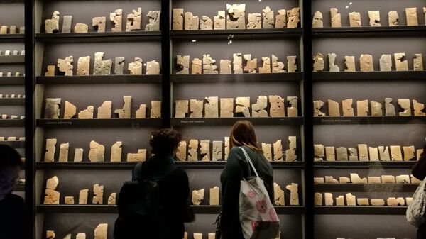 Visitors walk past a collection of 7th-century cuneiform texts from Ashurbanipal's personal library. - Sputnik International