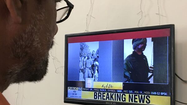 A man looks at a television screen displaying the pictures of the Indian pilots, said to be captured by Pakistan after shooting down two Indian planes, in Karachi, Pakistan February 27, 2019 - Sputnik International