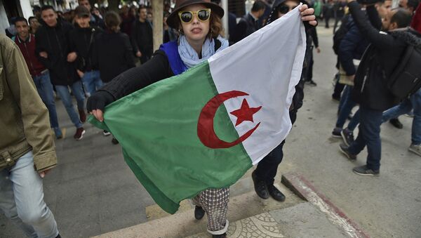 A woman holds an Algerian flag during demonstrations against President Bouteflika in Algiers on 26 February - Sputnik International