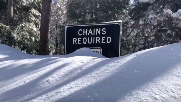 a chains required' sign on a snowed-in road  - Sputnik International
