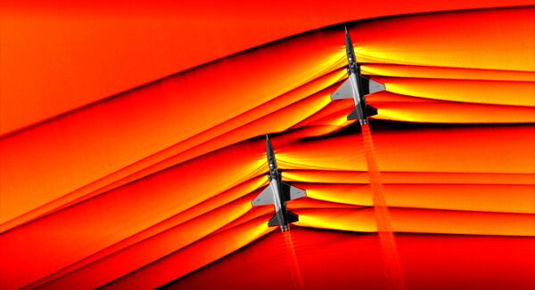Using the schlieren photography technique, NASA was able to capture the first air-to-air images of the interaction of shockwaves from two supersonic aircraft flying in formation. These two U.S. Air Force Test Pilot School T-38 aircraft are flying in formation, approximately 30 feet apart, at supersonic speeds, or faster than the speed of sound, producing shockwaves that are typically heard on the ground as a sonic boom. The images, originally monochromatic and shown here as colorized composite images, were captured during a supersonic flight series flown, in part, to better understand how shocks interact with aircraft plumes, as well as with each other. - Sputnik International