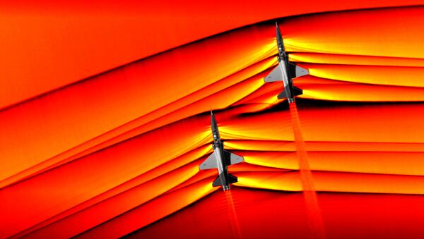 Using the schlieren photography technique, NASA was able to capture the first air-to-air images of the interaction of shockwaves from two supersonic aircraft flying in formation. These two U.S. Air Force Test Pilot School T-38 aircraft are flying in formation, approximately 30 feet apart, at supersonic speeds, or faster than the speed of sound, producing shockwaves that are typically heard on the ground as a sonic boom. The images, originally monochromatic and shown here as colorized composite images, were captured during a supersonic flight series flown, in part, to better understand how shocks interact with aircraft plumes, as well as with each other. - Sputnik International
