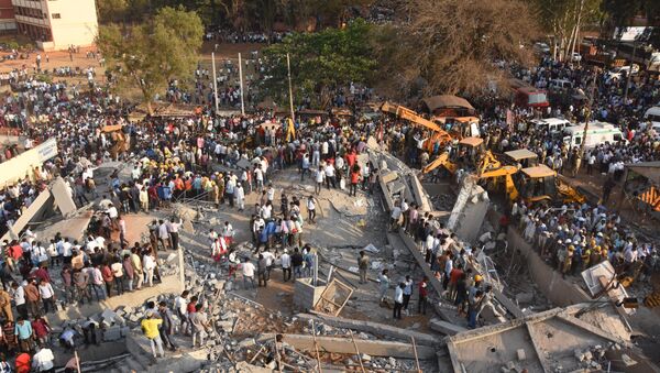 Onlookers gather near the rubble while rescue team search for survivors after an under-construction multi-storey building collapsed in Dharwad district of Karnataka - Sputnik International
