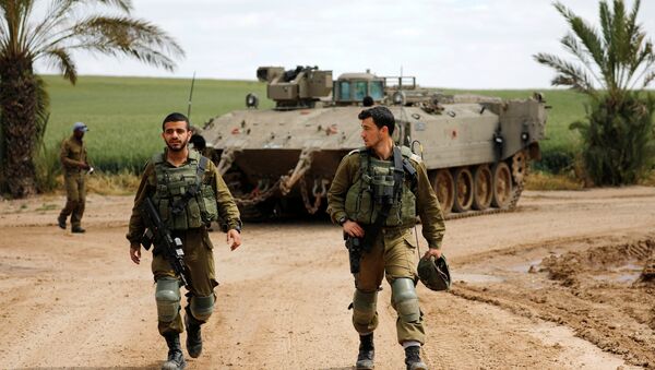 Israeli soldiers walk by an armoured personnel carrier (APC) near the border between Israel and Gaza on its Israeli side, March 15, 2019 - Sputnik International