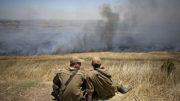  Israeli soldiers sit in a position on the Israeli-controlled Golan Heights as smoke rises following explosions of mortar shells (File) - Sputnik International