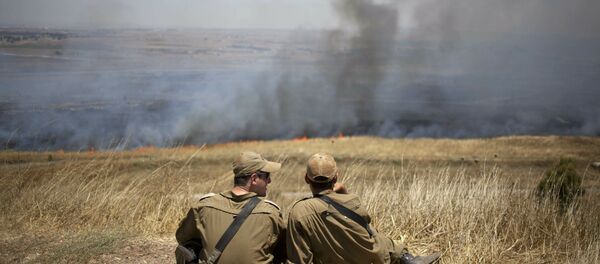 Israeli soldiers sit in a position on the Israeli-controlled Golan Heights as smoke rises following explosions of mortar shells (File) - Sputnik International
