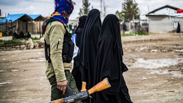 Foreign women, living in al-Hol camp which houses relatives of Islamic State (IS) group members, walk under the supervision of a fighter of the Syrian Democratic Forces (SDF) in the camp in al-Hasakeh governorate in northeastern Syria on March 28, 2019 - Sputnik International