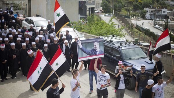 Druze men carry Syrian flags and pictures of Syrian President Bashar Assad during a rally marking Syria's Independence Day, in the Druze village of Ein Qiniyye, Israeli-controlled Golan Heights, Tuesday, April 17, 2018. - Sputnik International