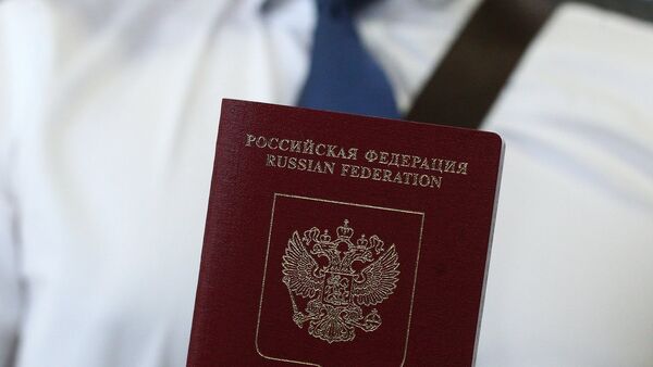 An employee of a passport and visa center demonstrates a foreign travel passport with additional biometric personal data - Sputnik International
