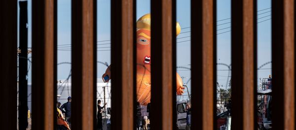 A satirical balloon of a baby US President Donald Trump is seen through the US-Mexico border fence during a demonstration against him prior to his visit to Calexico, California, as seen from Mexicali, Baja California state, Mexico, on April 5, 2019. - Sputnik International